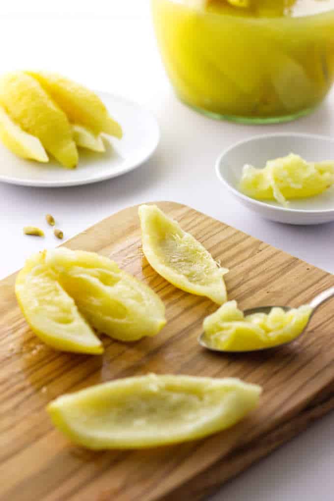 Preserved lemons in jar, on saucer, on cutting board and in a dish