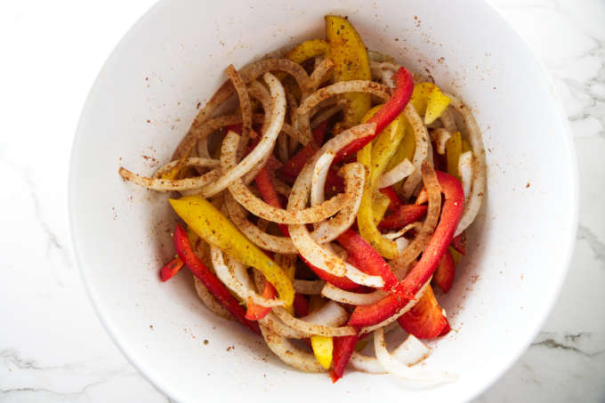Fajita vegetables in a bowl with fajita seasoning.