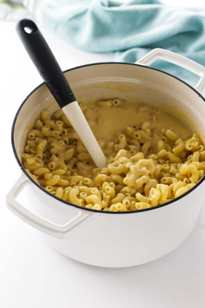 Stirring pasta into a pot of cheese sauce.