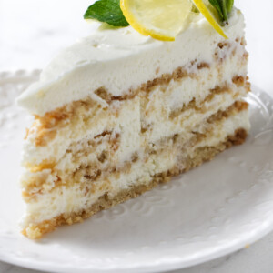 A slice of lemon cake garnished with lemon and mint.